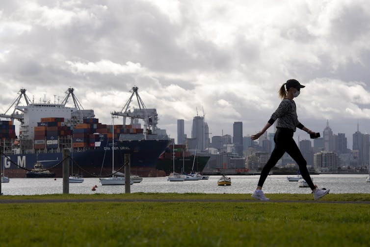 A woman walks wearing a mask.