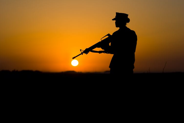 Silhouette of a female soldier holding a gun.