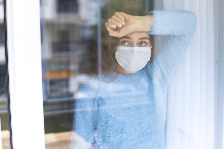 Girl wearing mask looking out window