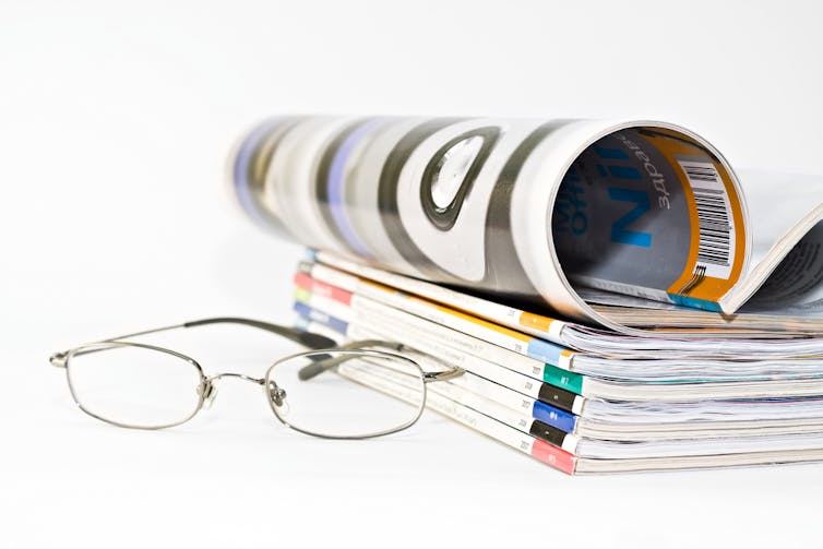 Pile of medical journals next to a pair of spectacles