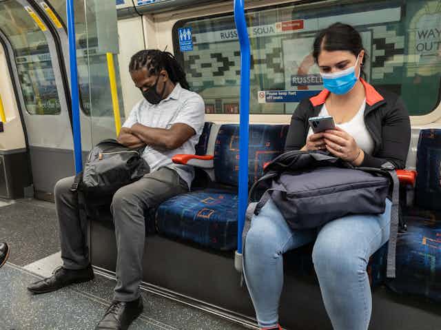 Man and woman on London Underground wearing masks.