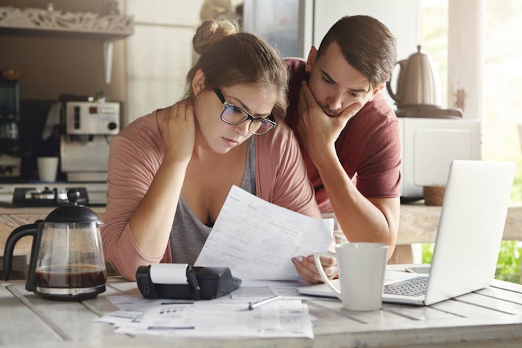Young couple in kitchen looking at household bills