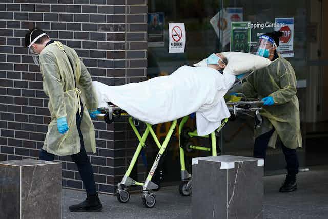Two health workers transporting an unwell aged care resident