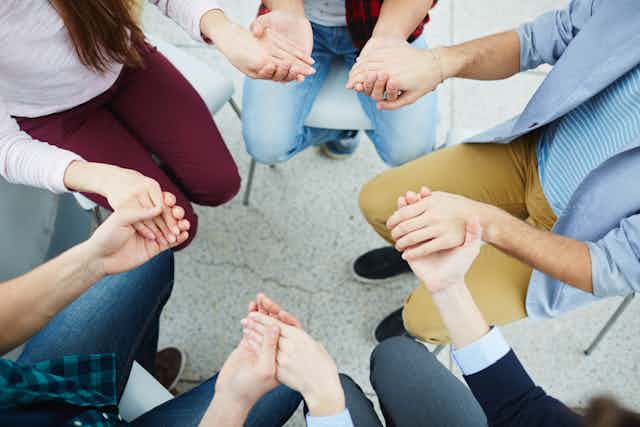 People sitting in a circle, holding hands