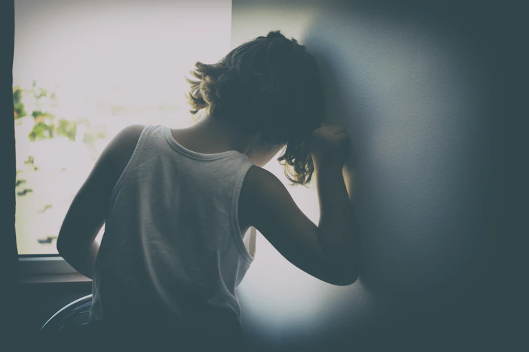 young child leaning on wall