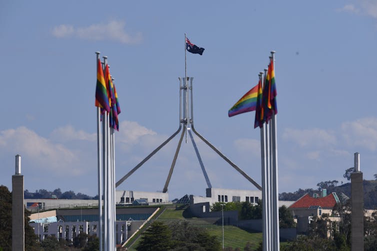 Rainbow flags flying against background of Parliament House, Canberra