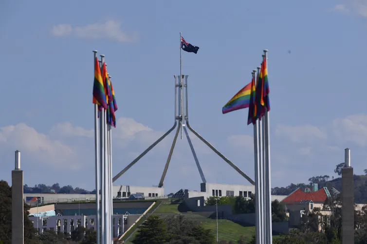 Rainbow flags flying against background of Parliament House, Canberra