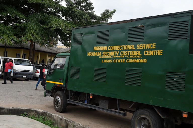 People walk past truck used fro conveying inmates to the prison in Lagos State High Court, Ikeja, Lagos, Nigeria