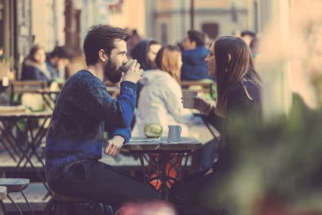 Couple drinking coffee at an outside table.