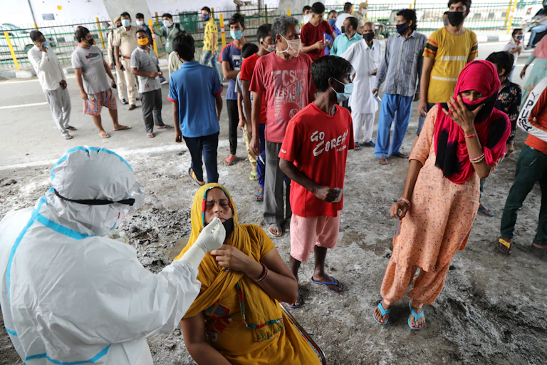 A paramedic takes a nasal swab sample from a woman.