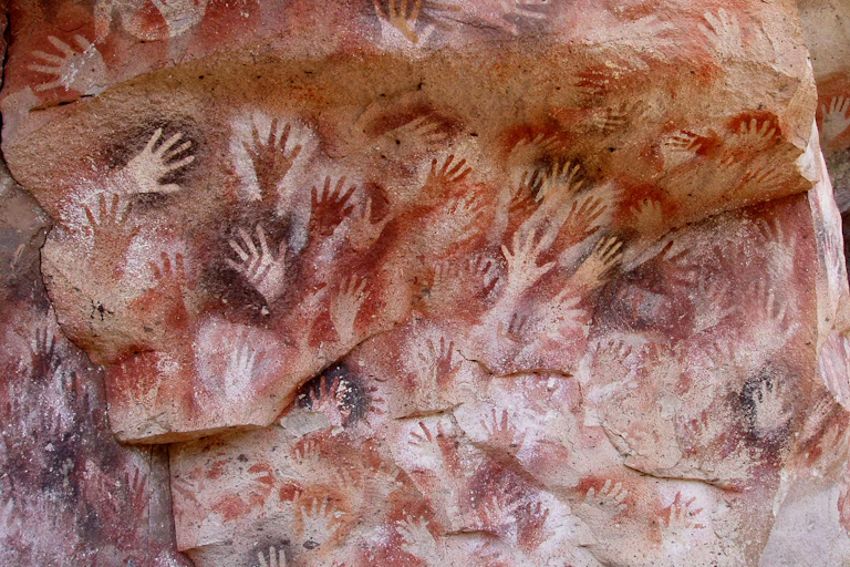 Handprint stencils painted on cave wall.
