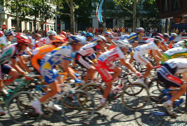 Ciclistas pasando a gran velocidad por una calle de ciudad francesa.