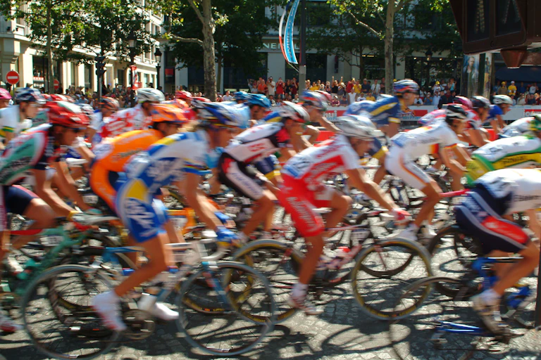 Ciclistas pasando a gran velocidad por una calle de ciudad francesa.