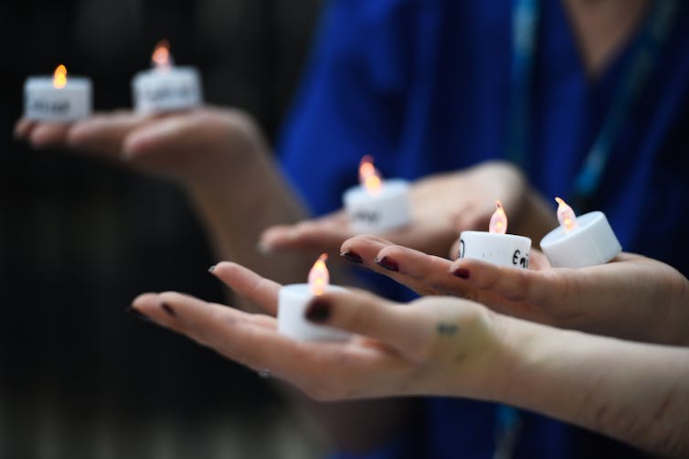 Three pairs of hands holding candles.