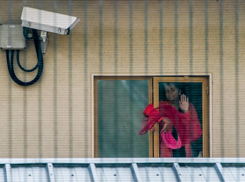 Woman at window of detention centre.