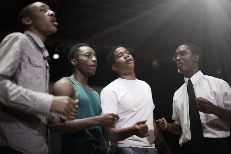 Four Black teen singing together.