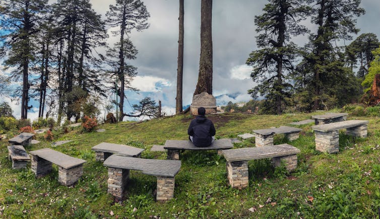 person seated on stone bench in outdoor preaching area