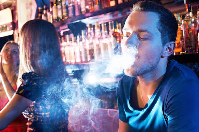 A smoker in a busy bar.
