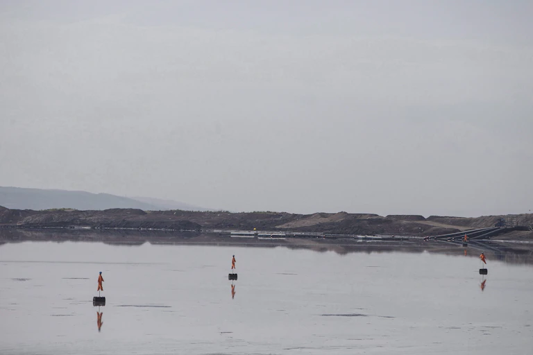 Body of water with floating scarecrows and embankments in the background