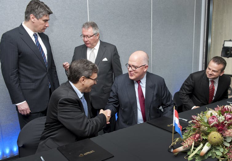 Men in business suits shake hands over an agreement