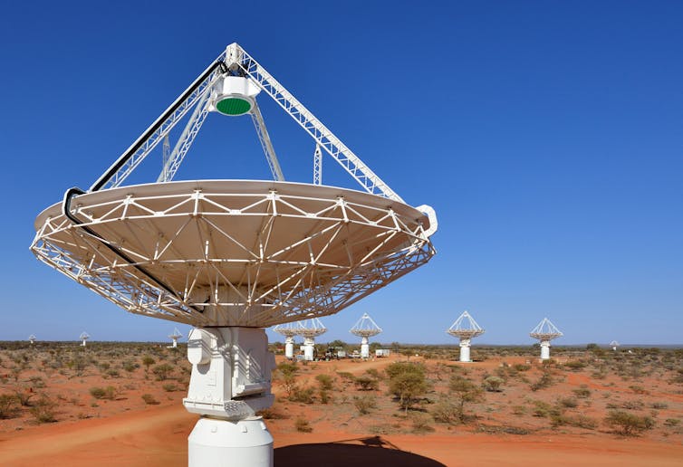 Antennas and a satellite dish in the foreground, with others in the background, in the WA desert.