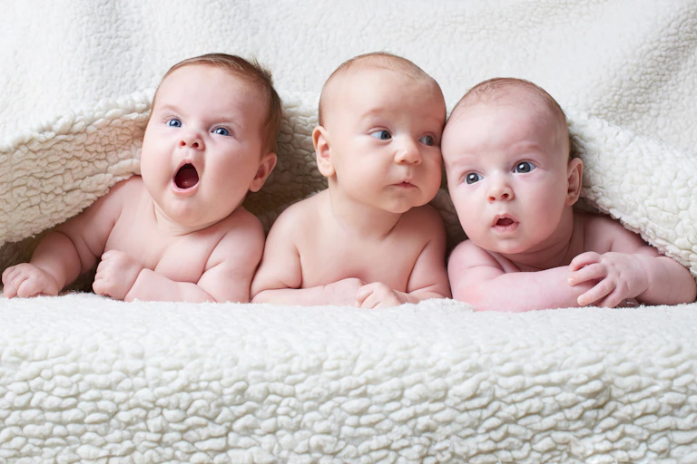 Three babies under a blanket.