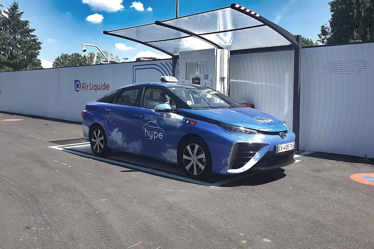Voiture bleue à une station de ravitaillement hydrogène.
