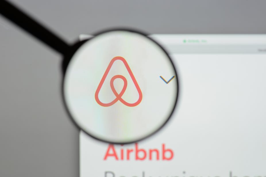 Airbnb logo behind a magnifying glass.