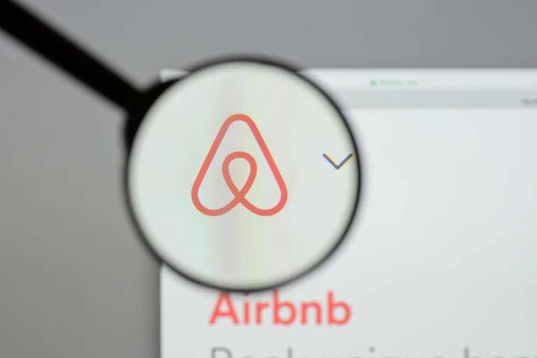Airbnb logo behind a magnifying glass.