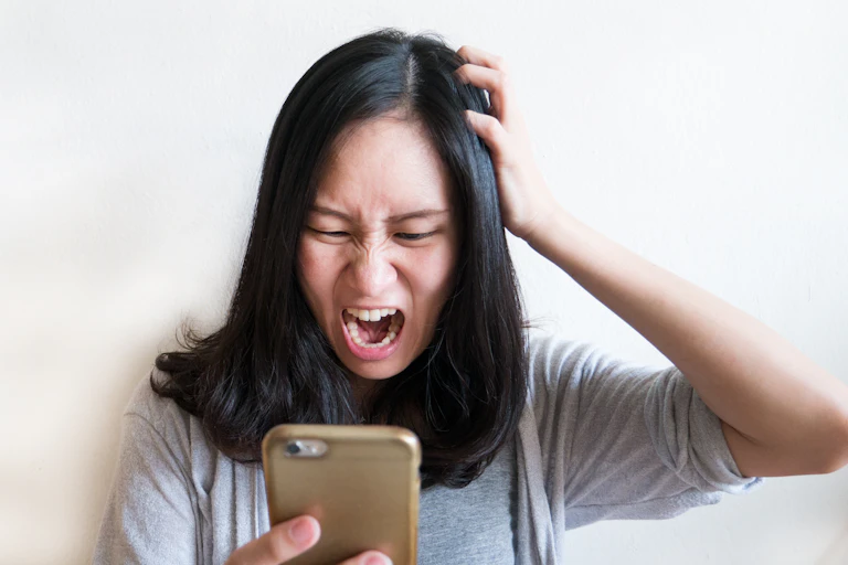 Angry woman staring at phone screen.