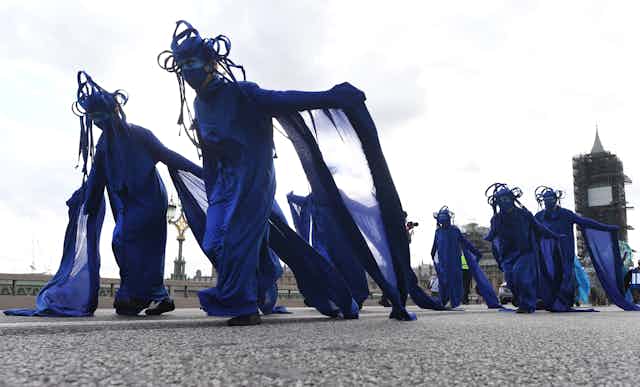 Protesters in blue dresses march down Westminster Bridge in London, UK.