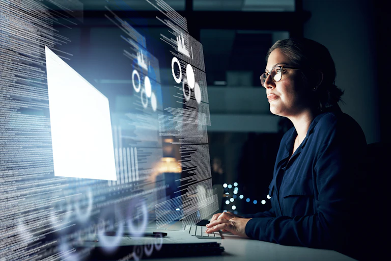 Woman typing in front of massive computer screen full of programming code.