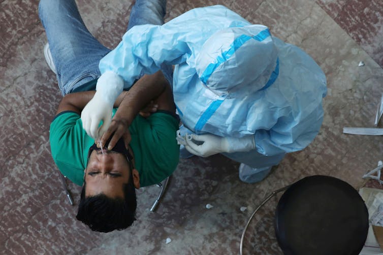 Paramedic takes nasa swab from man.