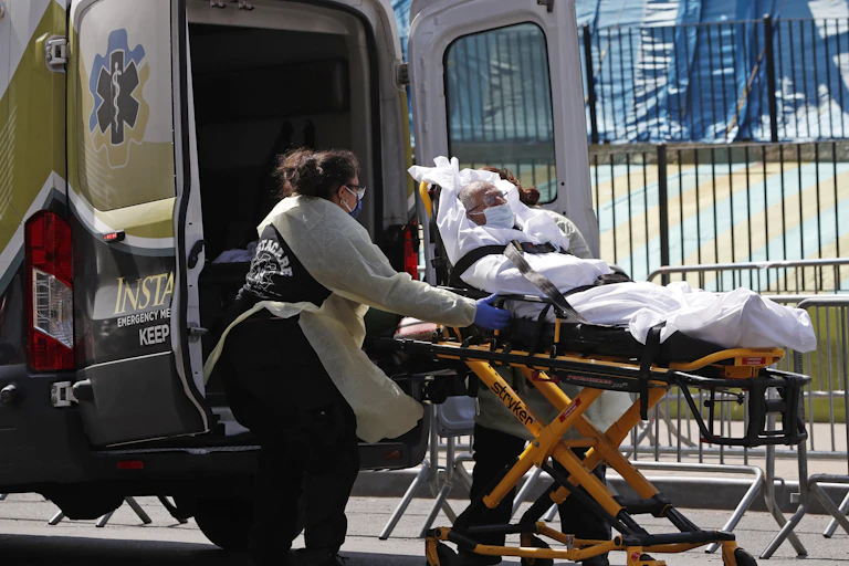 An older man being wheeled on a gurney into an ambulance. i