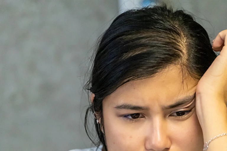 A woman disappointedly stares at her laptop screen.