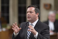Jason Kenney raises his hands in front of him as he speaks in the House of Commons.