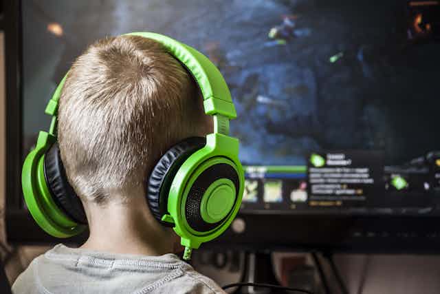 Boy playing computer game with headphones on.