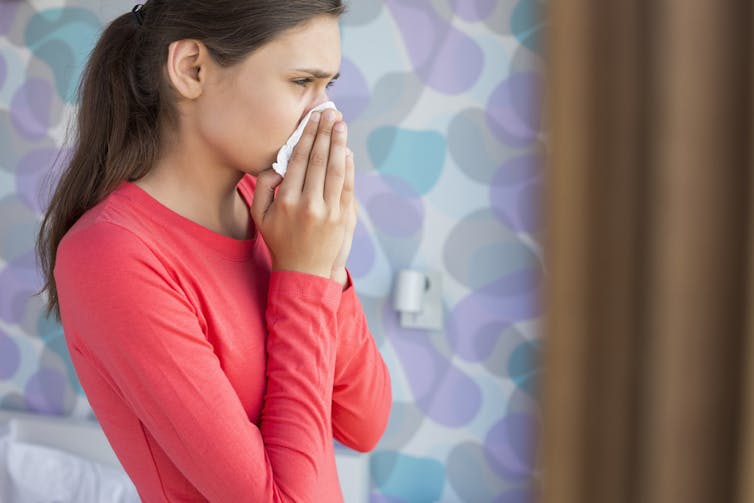 Young woman with a cold blowing her nose