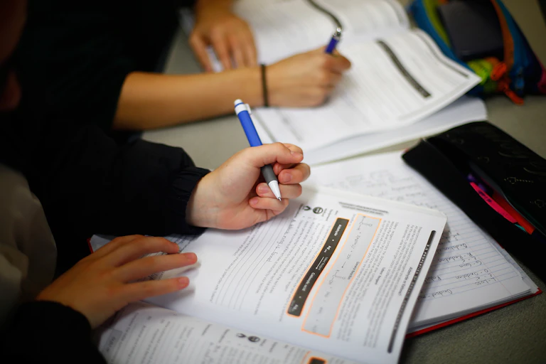 hands holding pens and school books