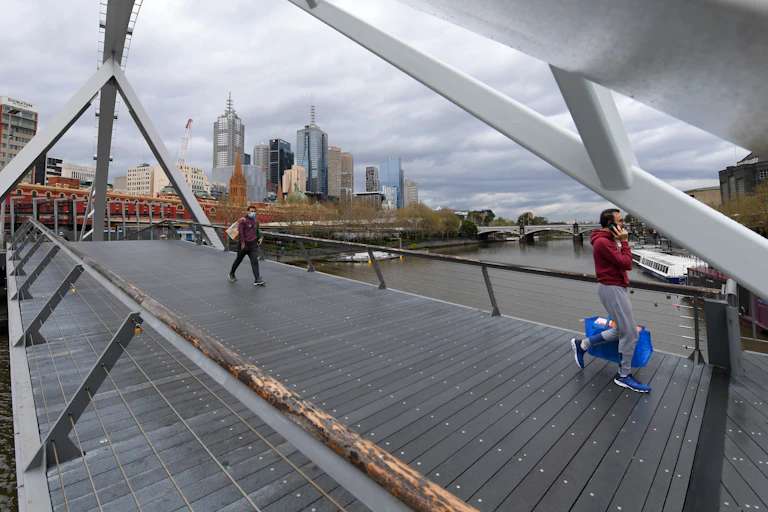 Two people walking across a footbridge in Melbourne.