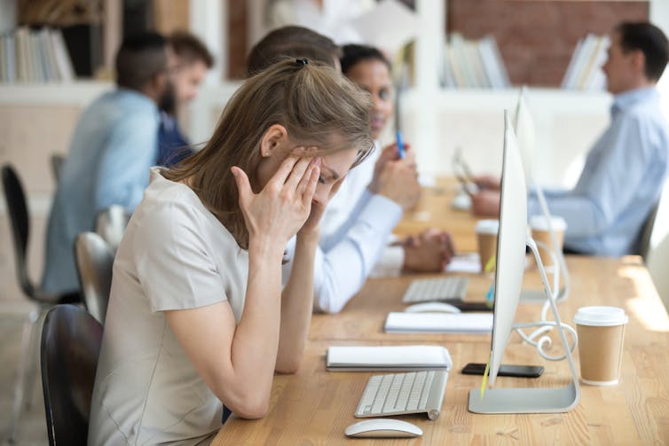 A woman at an office job with a headache