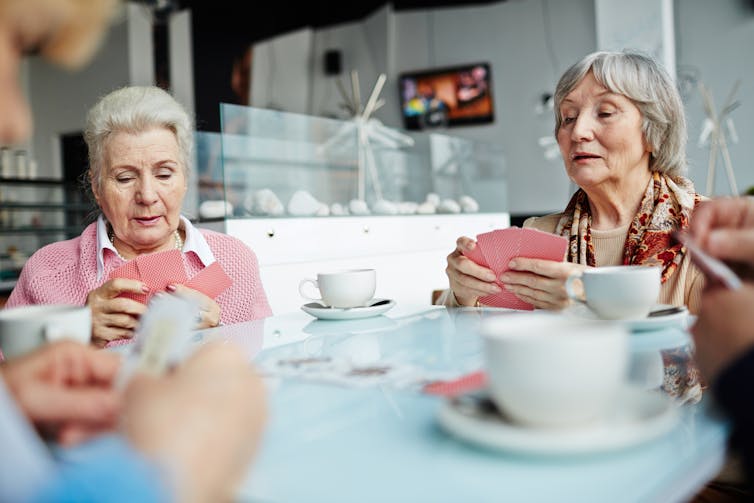 Women playing bridge around a table at home