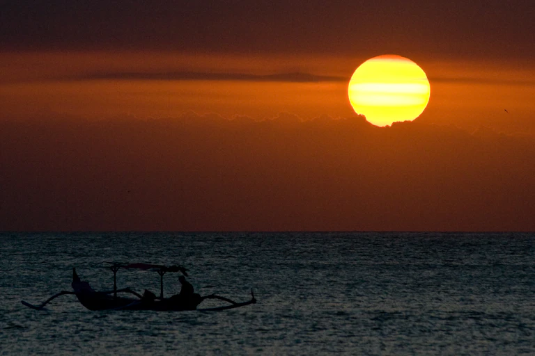 A traditional boat in the sea at a hot sunset in Bali.