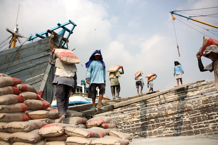 People unloading cargo in the outdoors at Jakarta port.