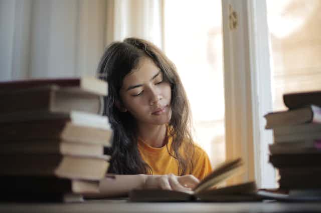 Girl reading surrounded by books