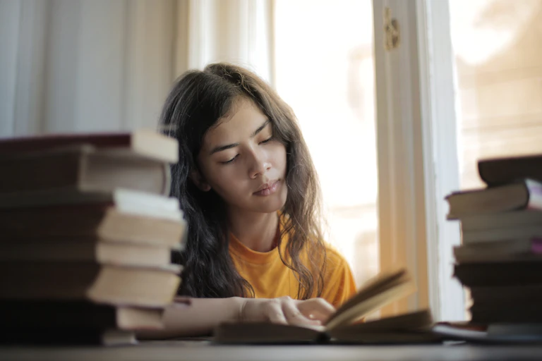Girl reading surrounded by books