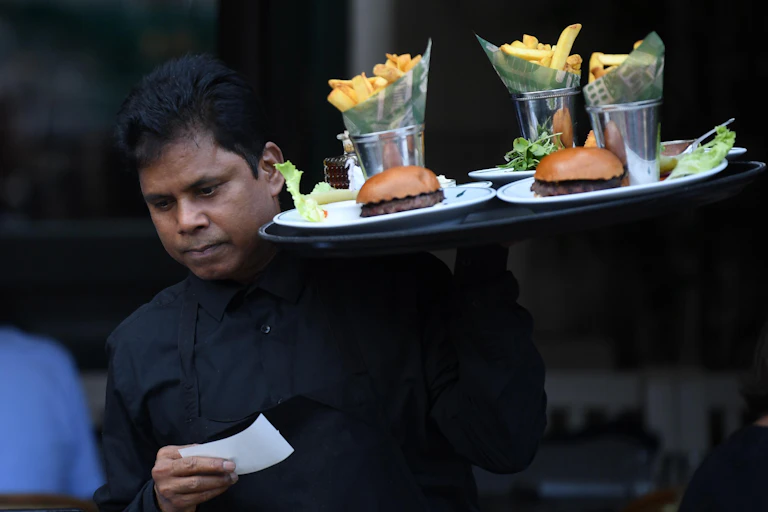 London waiter carrying tray with burgers and chips