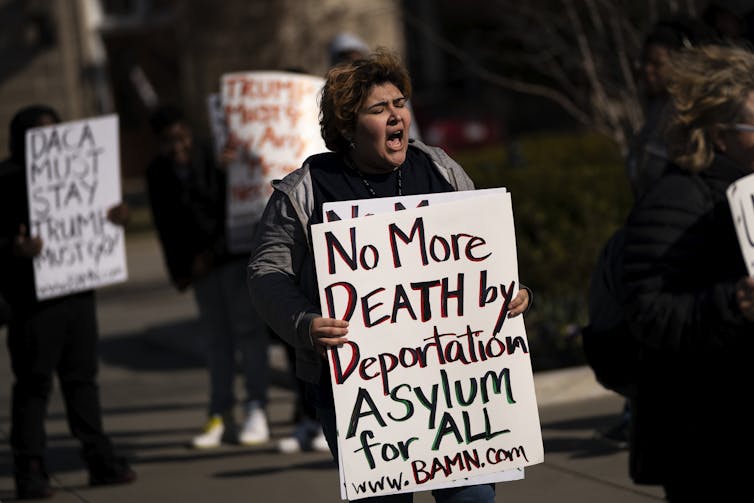 A woman holding a sign that says