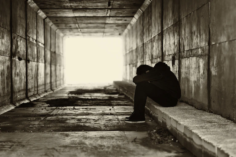 Boy with head in hands in tunnel