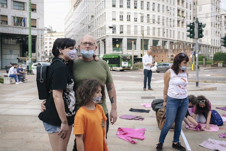 A woman, man and girl stand in a square in Milan to protest domestic violence.